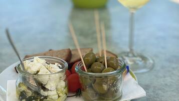 A table with a plate of food, a glass of white wine, and a green plant in the background.