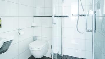 Un baño moderno con lavamanos, inodoro y cabina de ducha de vidrio.