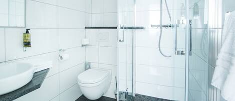 Un baño moderno con lavamanos, inodoro y cabina de ducha de vidrio.