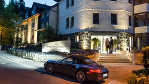 A hotel with a stone facade, a sign reading "Hotel am Herkulens," and a black car parked in front. - Hotel am Herkules - garni (Kassel)