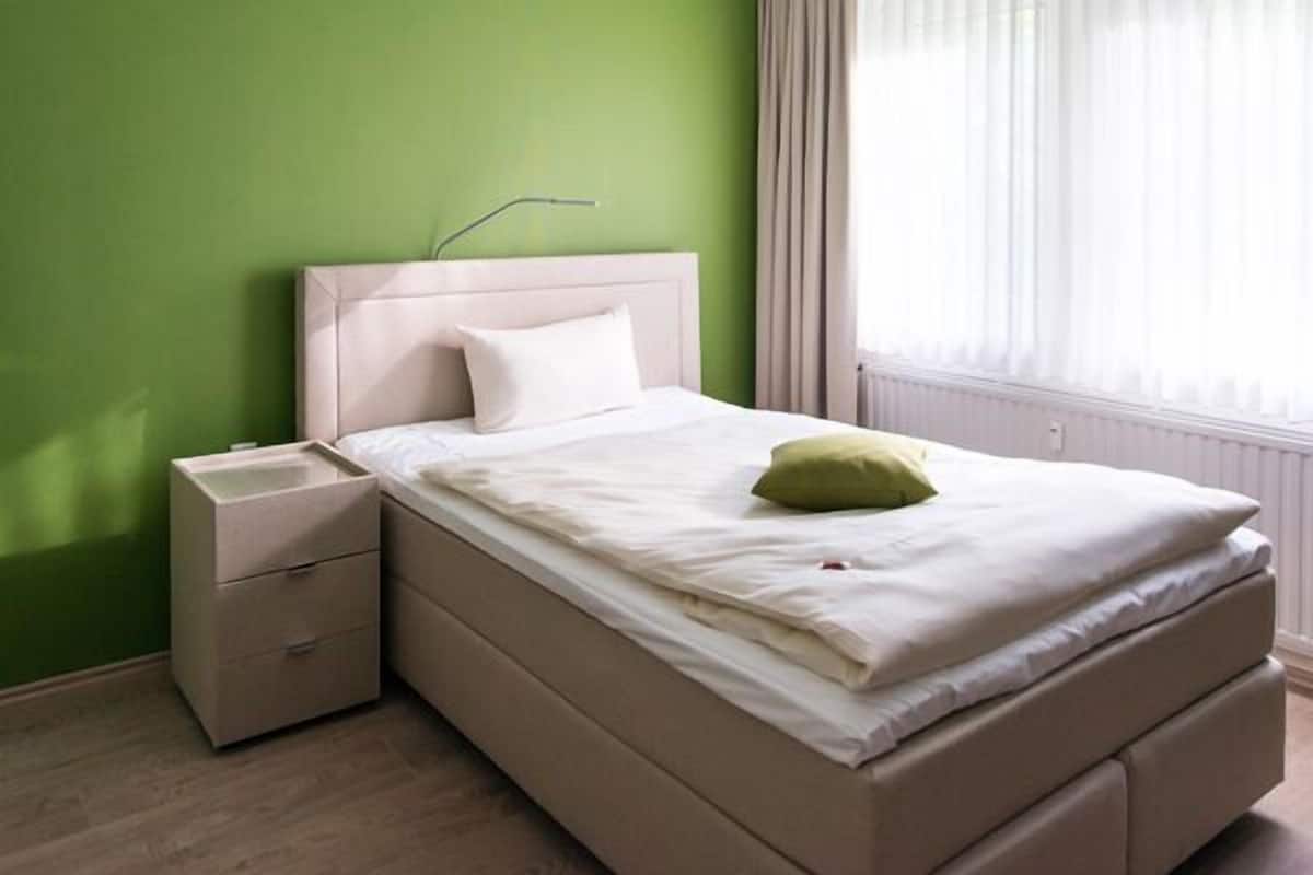 Een slaapkamer met een bed, nachtkastje en een raam met gordijnen.