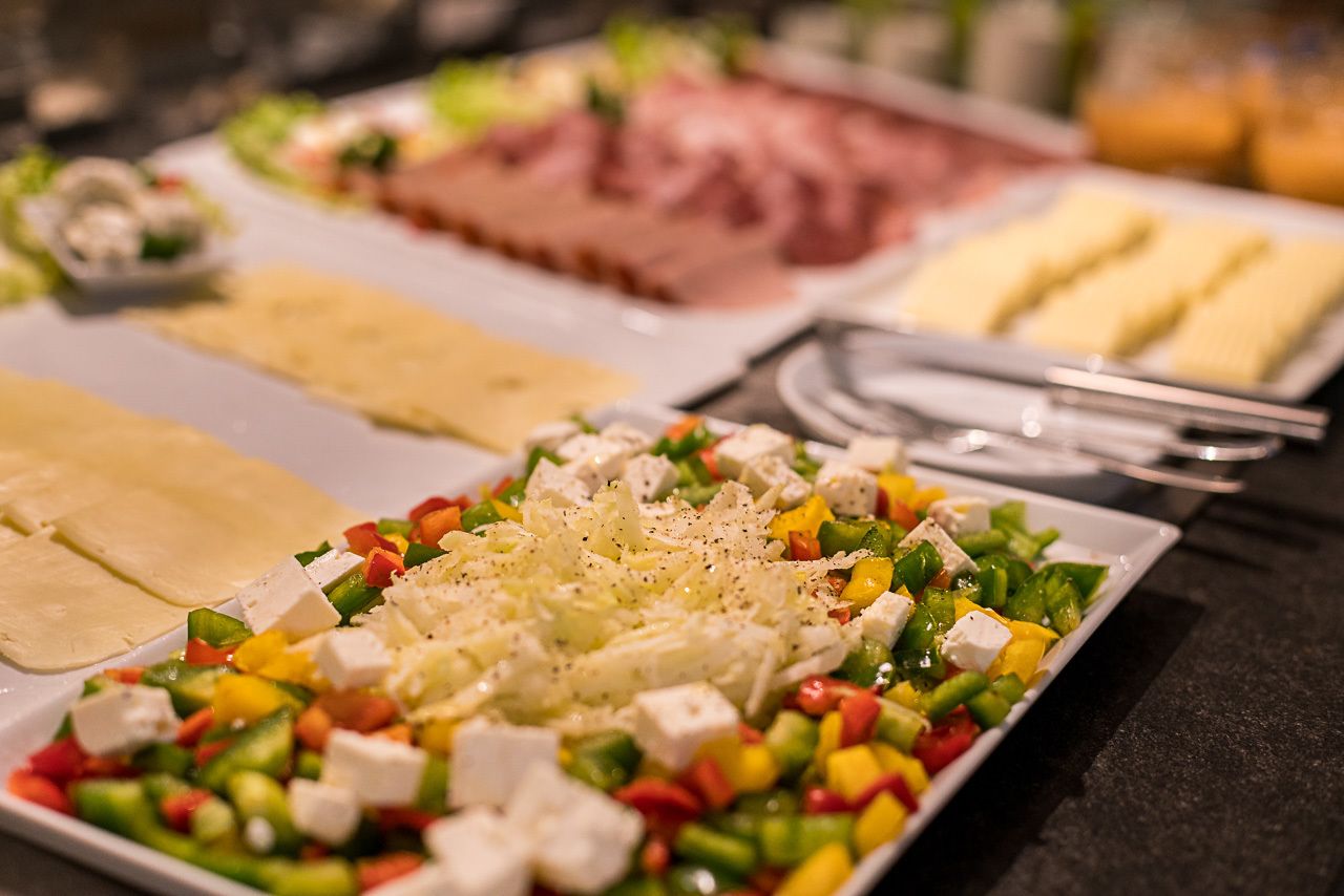 A buffet with various dishes including a salad with cheese and vegetables, and other food items.
