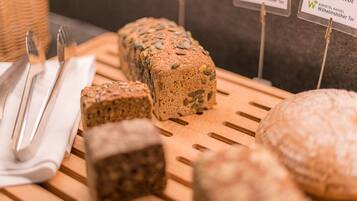 Verschiedene Brotsorten werden auf einer Holzbrett präsentiert, mit Schildern, die die jeweiligen Sorten kennzeichnen.