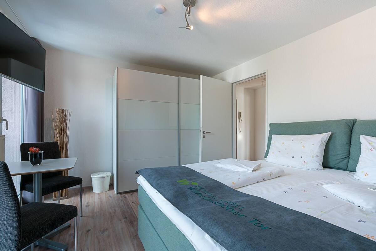 A hotel room with a bed, a desk, and a wardrobe.