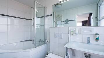 A modern bathroom with a glass-enclosed shower, a white bathtub, and a sink with a mirror above it.