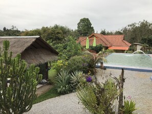 Ein Gebäude mit einem Reetdach, ein Schwimmbecken und ein Haus mit roten Ziegeldach.