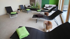 Un área interior moderna de relajación con sillones, un sofá y un perro pequeño.