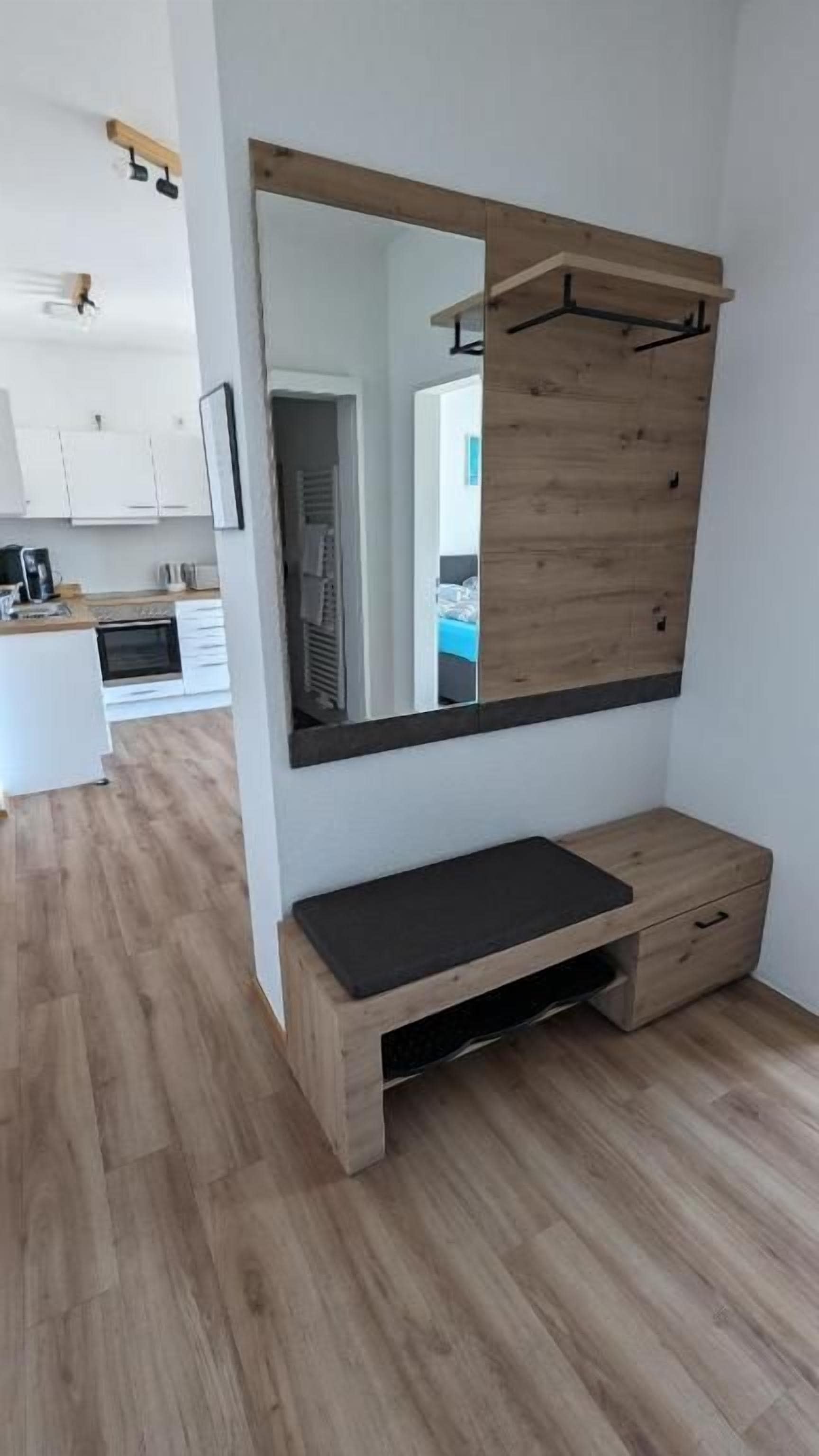 A room with a wooden bench, a mirror, and a wooden cabinet.