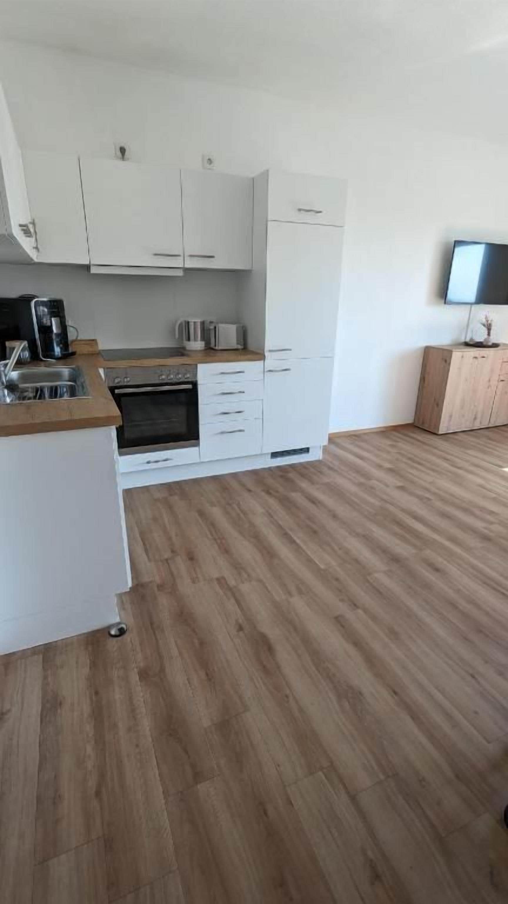 A modern kitchen with white cabinets, a built-in oven, and a coffee maker.