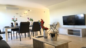 Una sala de estar moderna con comedor, televisor de pantalla plana y una mesa de centro.