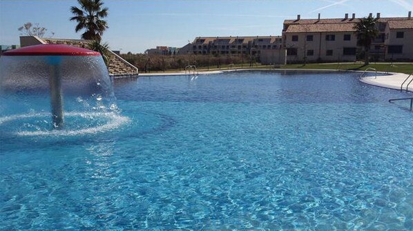 En swimmingpool med en vattenfontän, omgiven av byggnader.