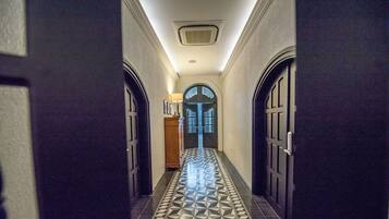 A hallway with patterned floor tiles, a central door with a blue geometric design, and two side doors.