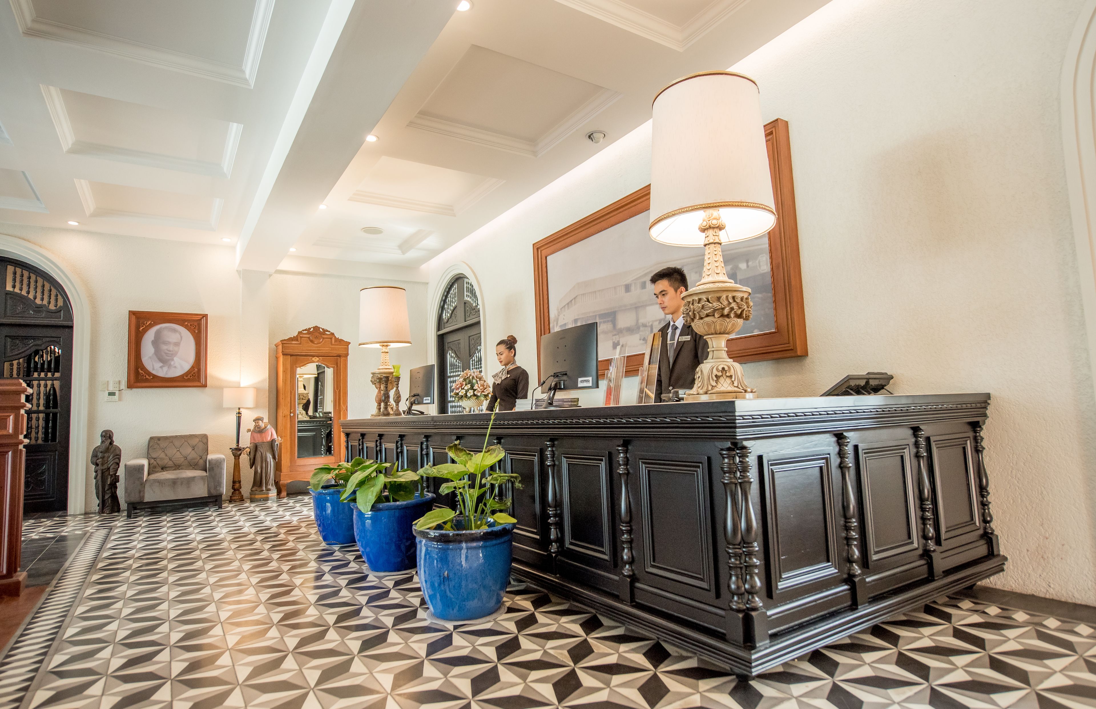A reception area with a black marble counter, blue potted plants, and a large mirror above the counter.