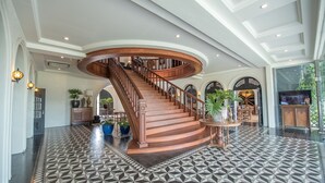 A grand spiral staircase in a spacious lobby with patterned flooring and elegant decor.