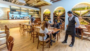 A restaurant with wooden tables and chairs, a bar area, and wine racks.