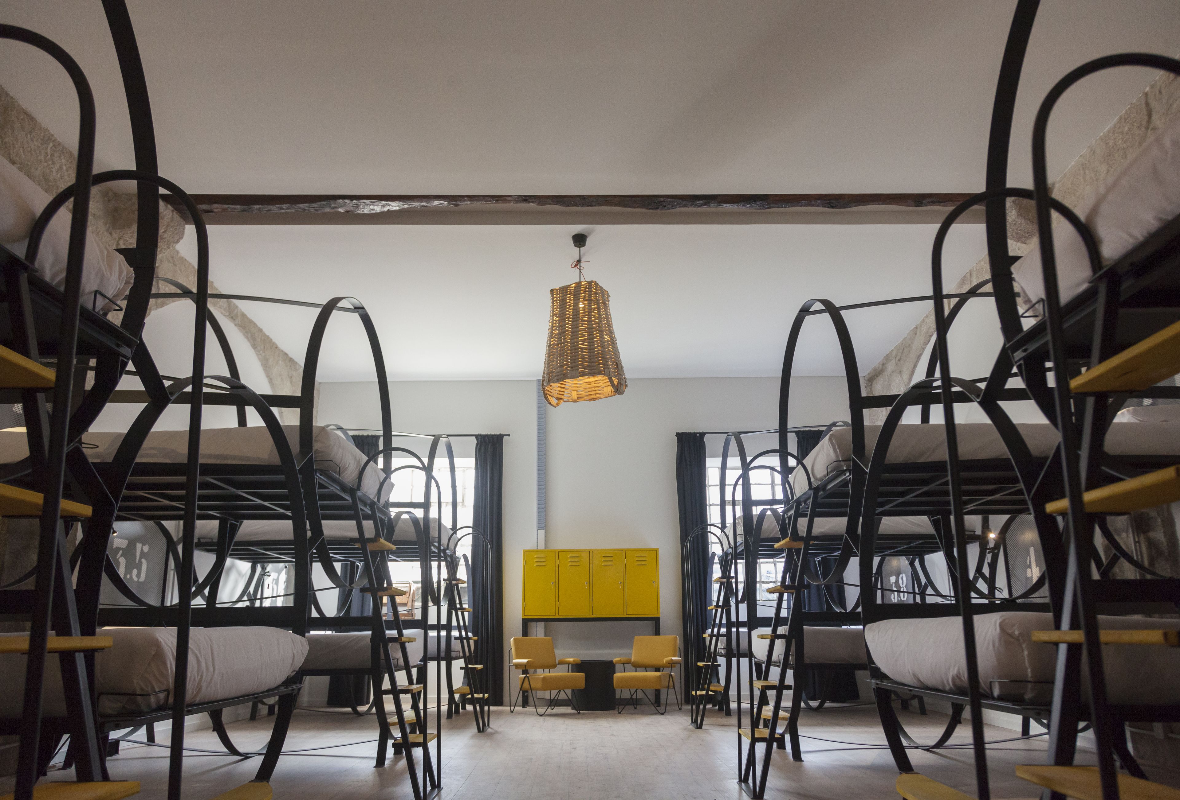 A room with bunk beds, a central table with chairs, and a hanging light fixture.