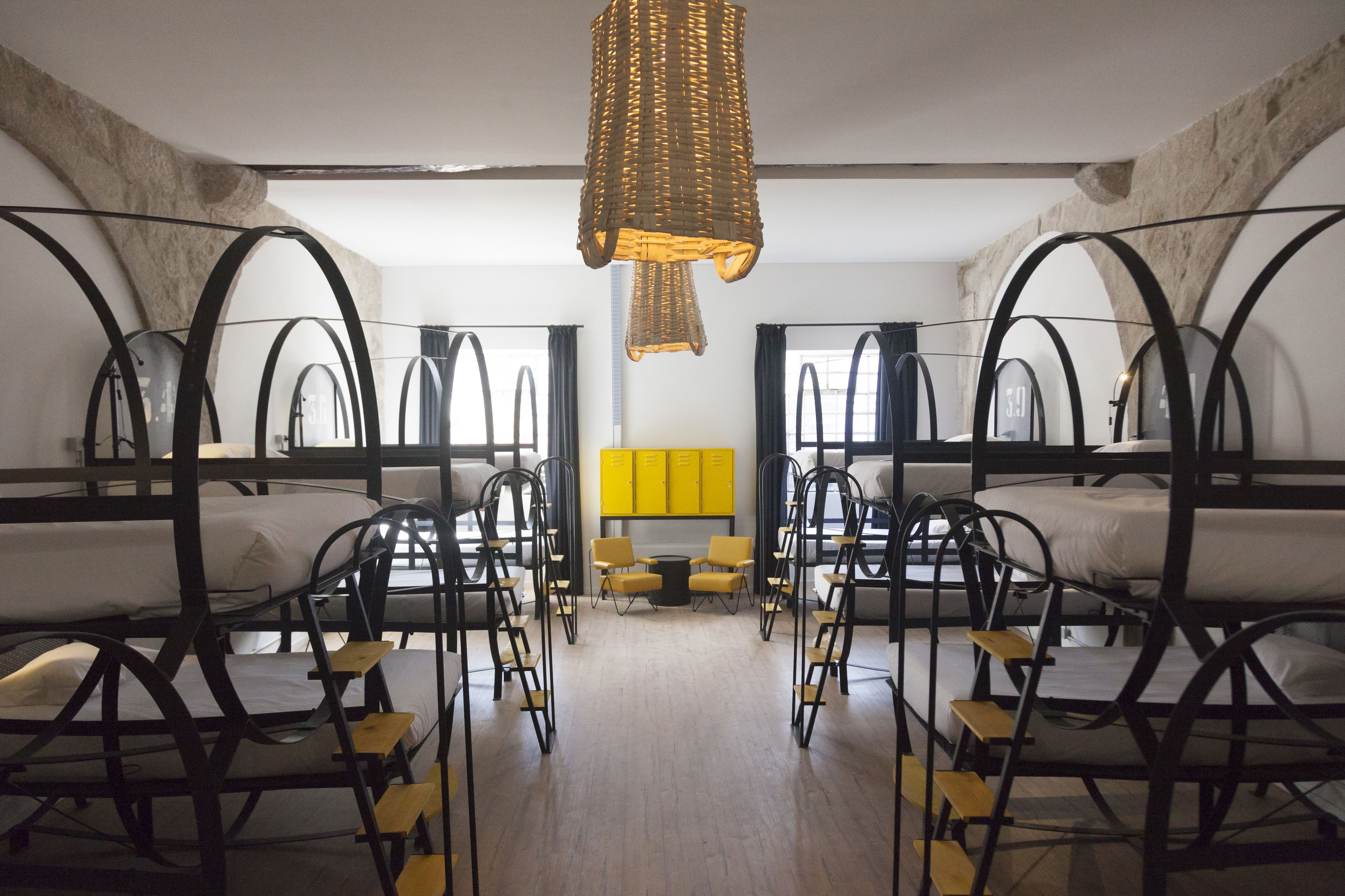 A room with bunk beds, a central table, and chairs.