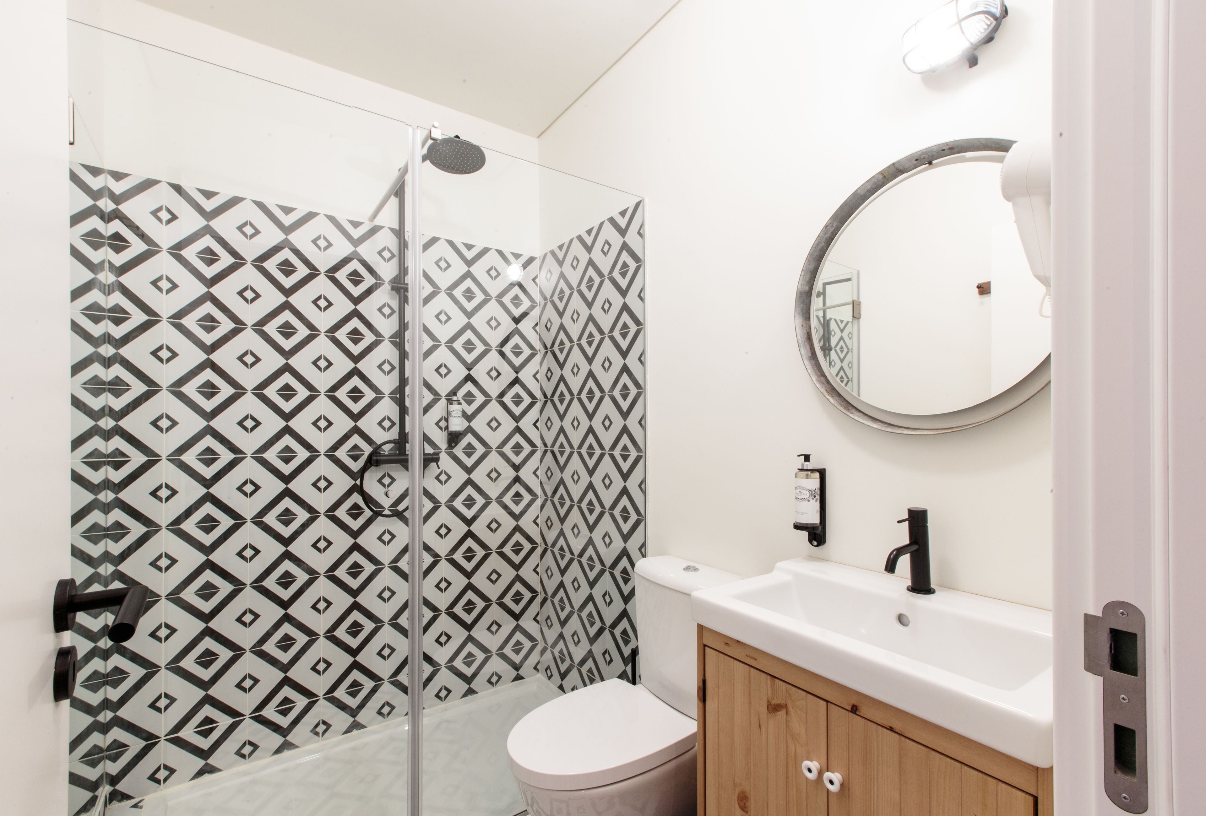 A bathroom with a shower, toilet, sink, and mirror.