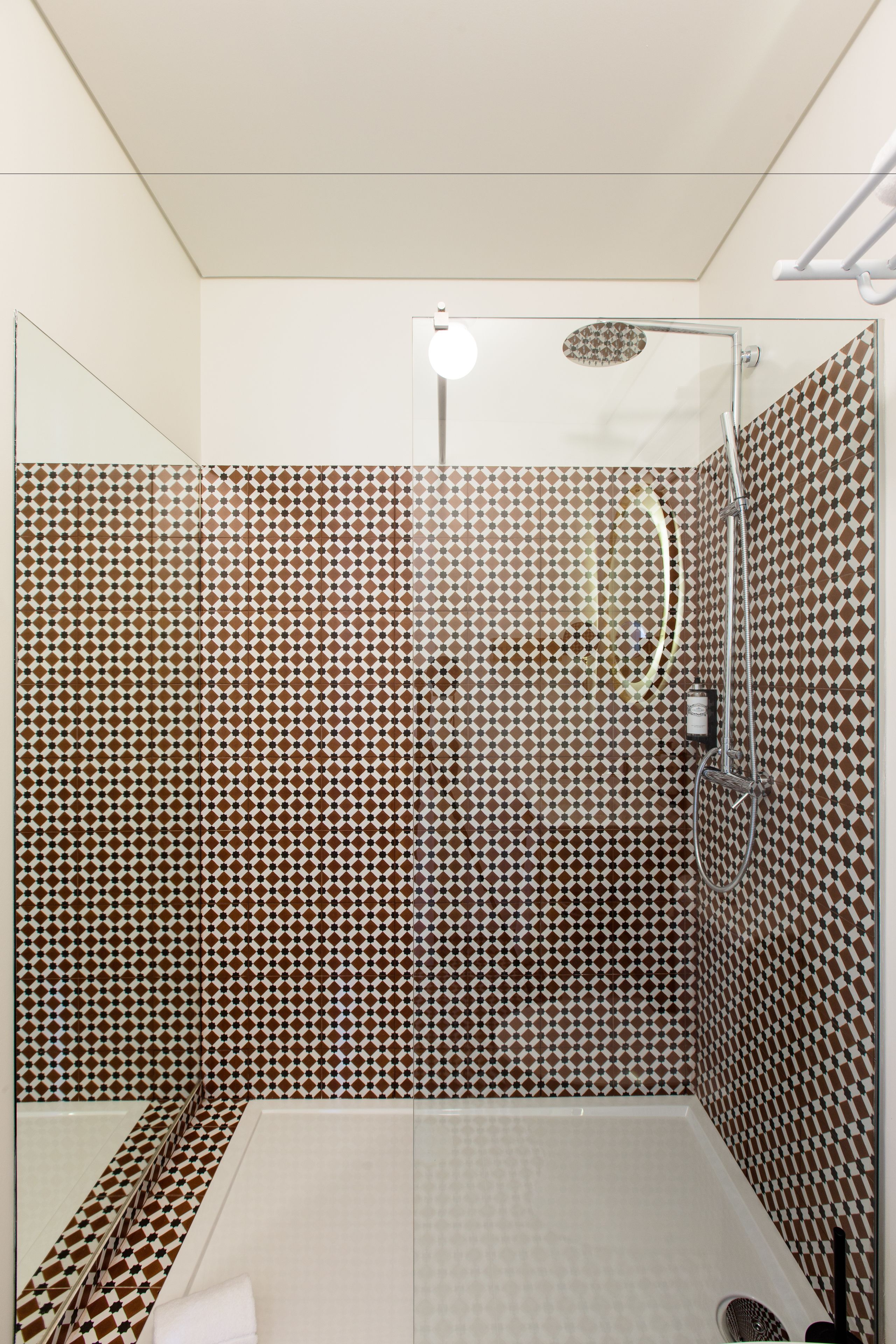 A shower with a geometric tile pattern on the walls and floor.