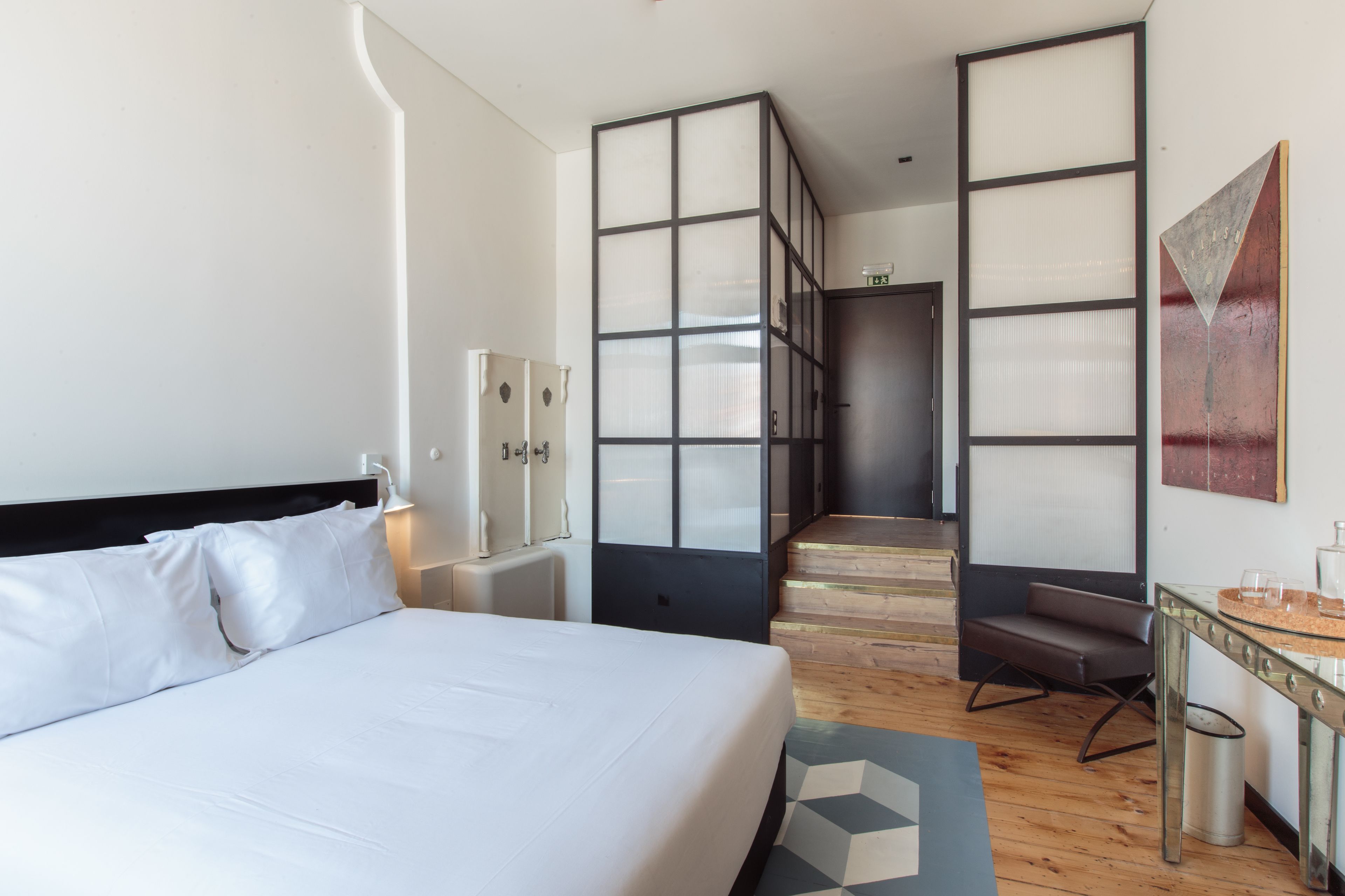 A hotel room with a large bed, a desk, a chair, and a staircase leading to another room.