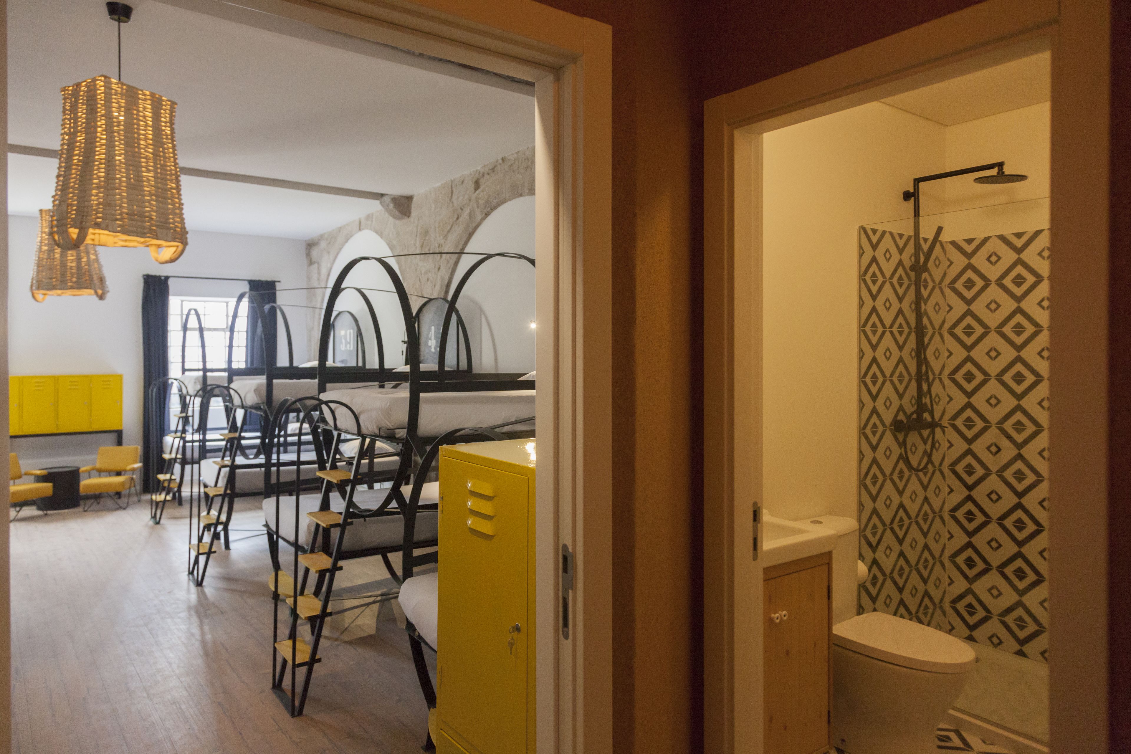A room with bunk beds, a yellow storage unit, and a shower with patterned tiles.