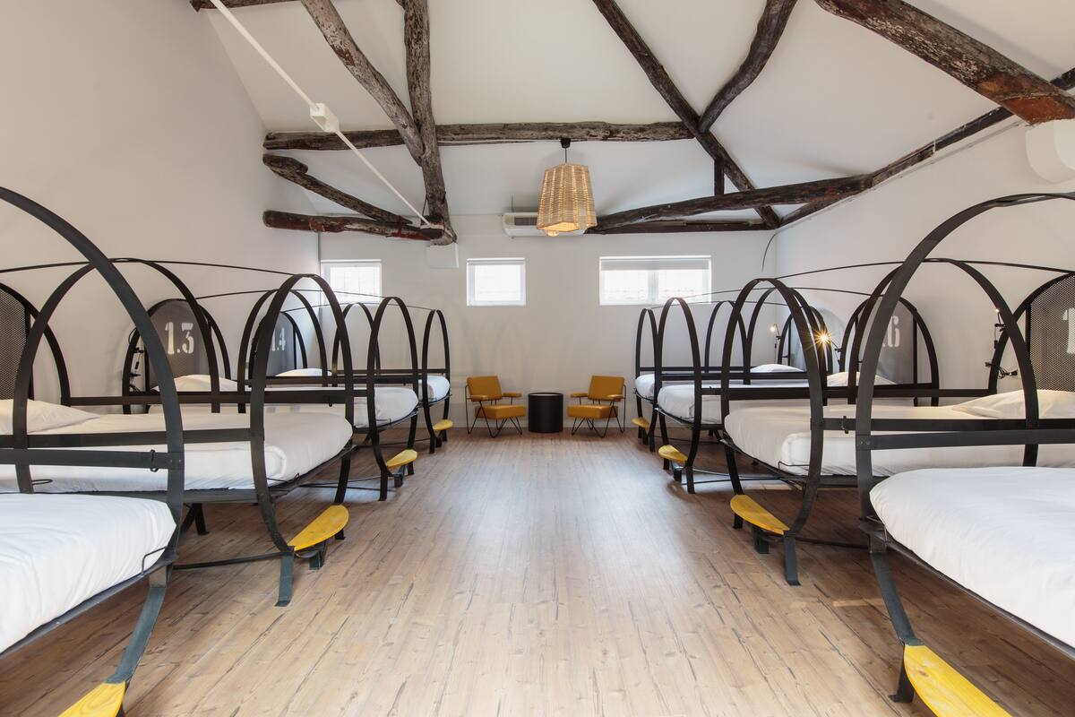 Une chambre avec des lits superposés, un plancher en bois et un plafond rustique.