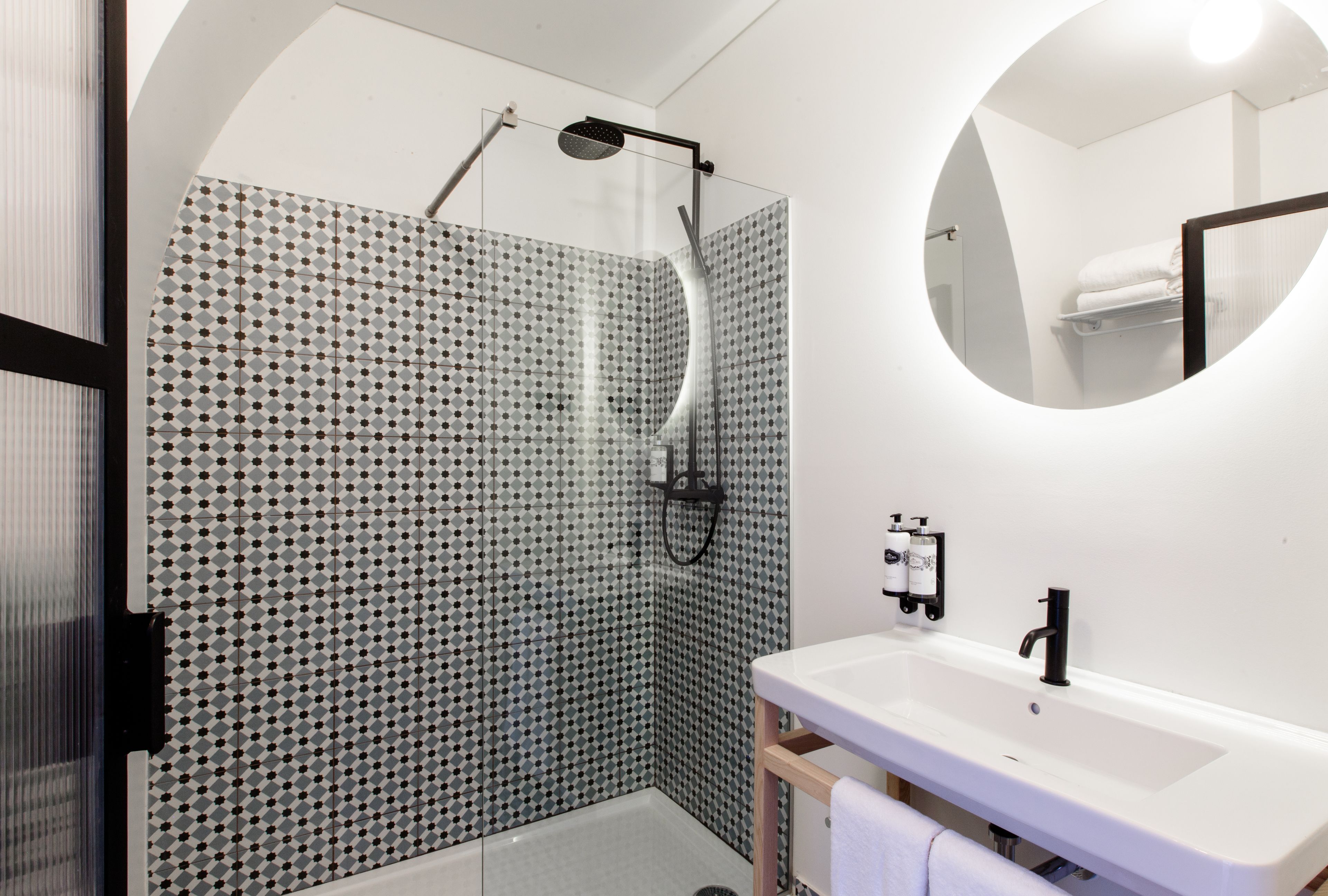 A modern bathroom with a shower, a sink, and a mirror.