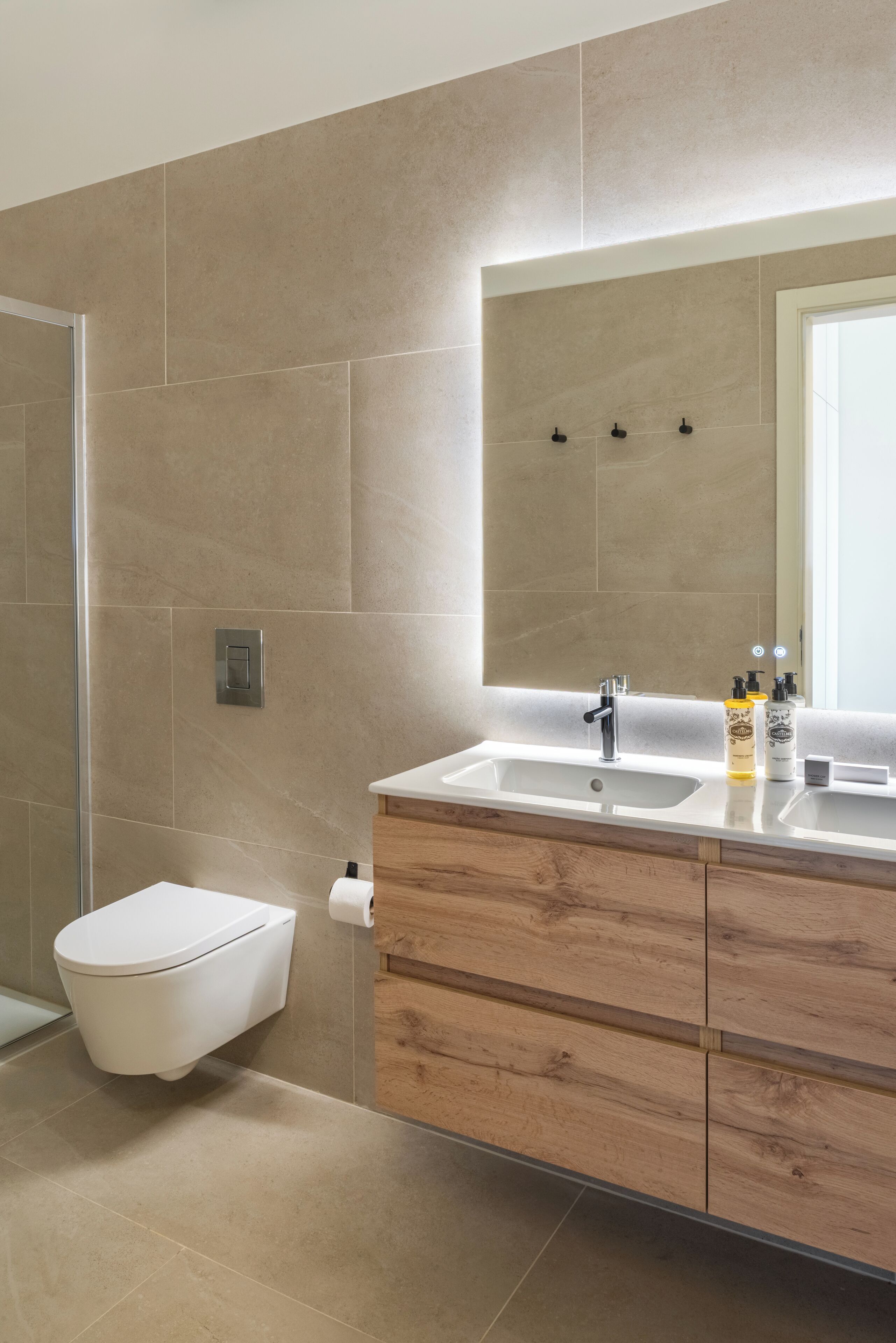 Ein modernes Badezimmer mit Toilette, Waschbecken mit Spiegel und Holzschränken.