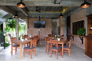 A spacious indoor dining area with brick walls, wooden tables and chairs, and hanging pendant lights. - Goodhope Villa (Sam Roi Yot)