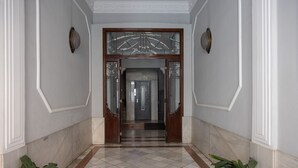 A hallway with a checkered floor, two potted plants, and a door with glass panels and a wooden frame. - Welcome to Ruzafa Oasis by Florit Flats (Valencia)