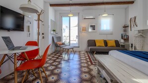 A modern room with a bed, a sofa, a dining table with chairs, a TV, and a large window. - Welcome to Ruzafa Oasis by Florit Flats (Valencia)