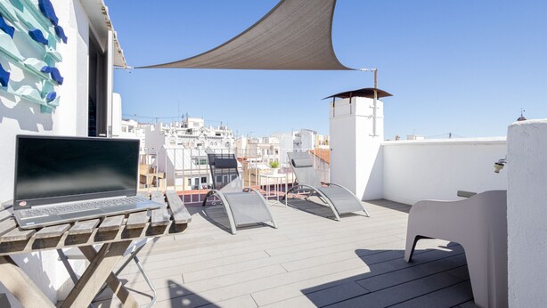 A rooftop terrace with a laptop, lounge chairs, and a view of a cityscape. - Welcome to Ruzafa Oasis by Florit Flats (Valencia)