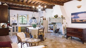 Un interior rústico con comedor, muebles de madera, chimenea y cocina al fondo.