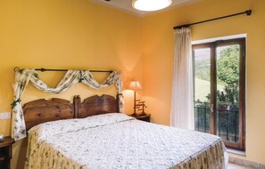 Une chambre à coucher avec un lit en bois, une table de chevet avec une lampe, une fenêtre donnant sur un paysage verdoyant et un rideau.