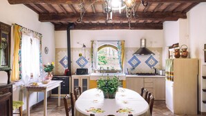Una cocina con mesa, sillas, estufa y ventana con vistas a zonas verdes.