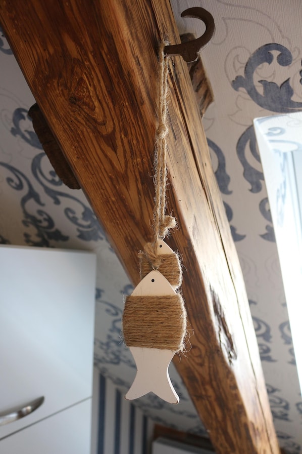 A wooden beam with a rope and a fish-shaped ornament hanging from it.
