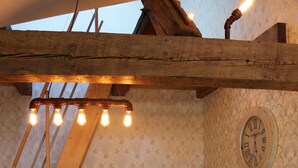 A cozy room with a wooden staircase, a cushioned sofa, a small table, and a wall clock. - Holiday loft on the water with cathedral view DG (Hansestadt Havelberg)