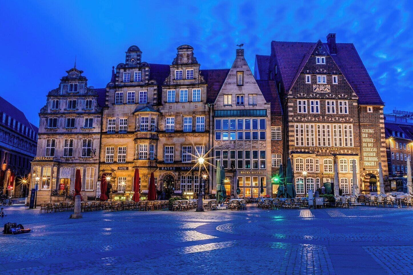 Una plaza histórica europea con pavimento de adoquines y edificios tradicionales de varios pisos y diversos estilos arquitectónicos.
