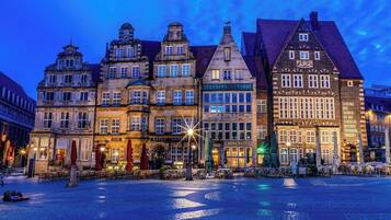 Una plaça europea històrica amb paviment de lladric i edificis tradicionals d'altures diverses i estils arquitectònics variats.