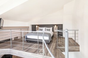 Ein modernes Schlafzimmer mit Bett, Kopfteil, Nachttischen und einer Treppe.