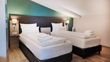 Ein Hotelzimmer mit zwei Betten, einer grünen Akzentwand und Nachttischlampen.