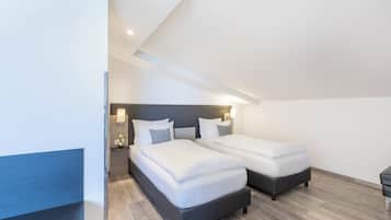 A modern bedroom with two beds, a nightstand, and a wall-mounted lamp.