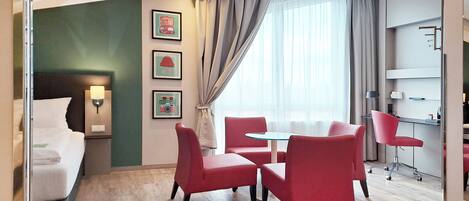 Una habitación de hotel con una cama, un escritorio, una silla, una mesa y una ventana con cortinas.