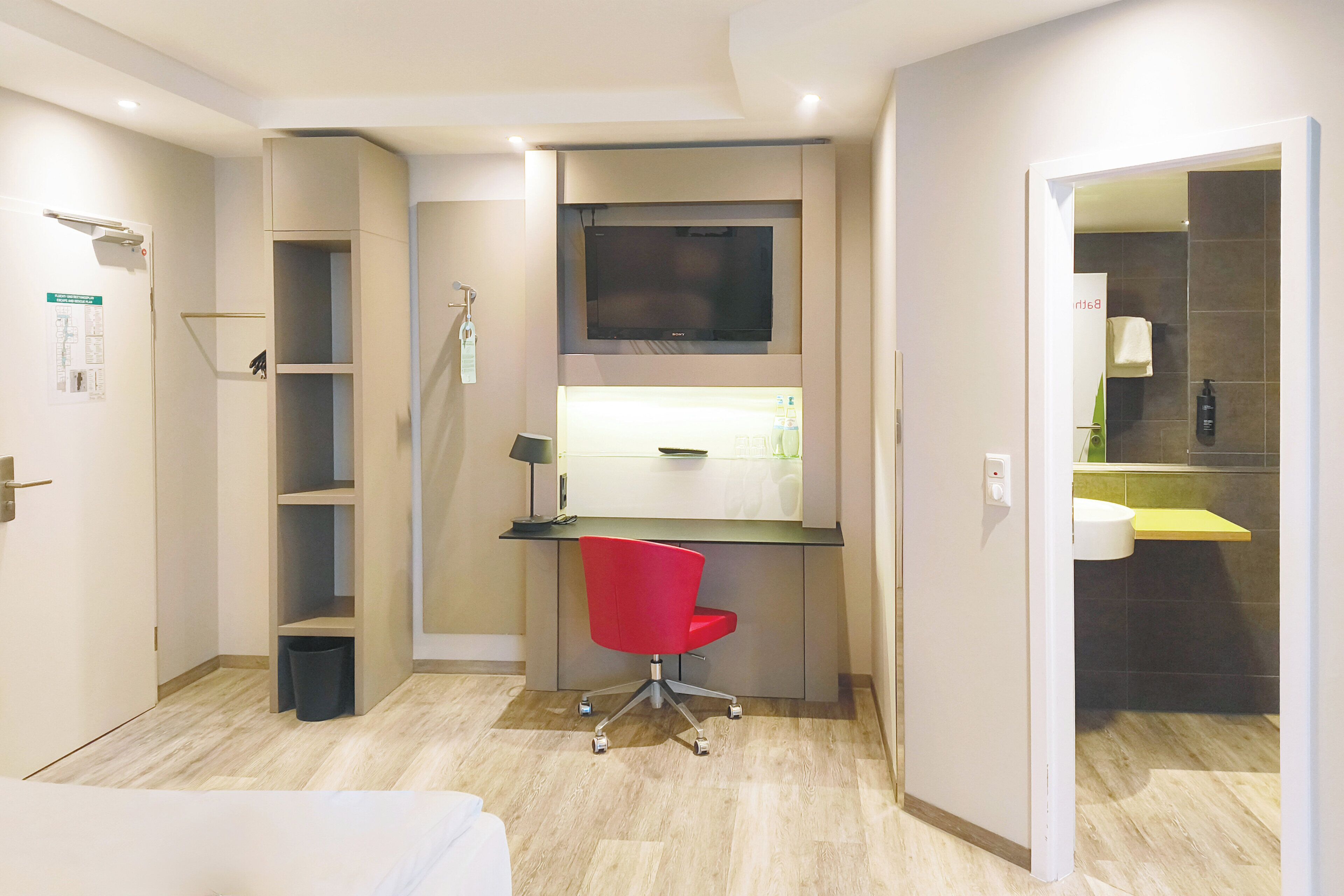 Une chambre d’hôtel moderne équipée d’un bureau, d’une chaise et d’une petite étagère.