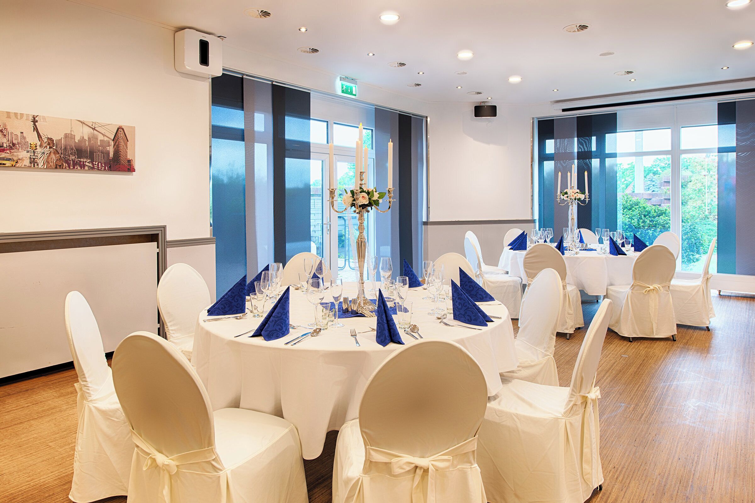A conference room with round tables, white chairs, and large windows.
