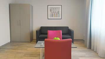 Ein modernes Wohnzimmer mit einer Couch, einem roten Sessel, einem Glastisch und einem Kleiderschrank.