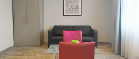 A modern living room with a sofa, a red chair, a glass table, and a wardrobe.