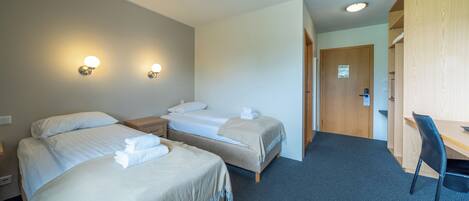 Une chambre d’hôtel avec deux lits, un bureau et une chaise.