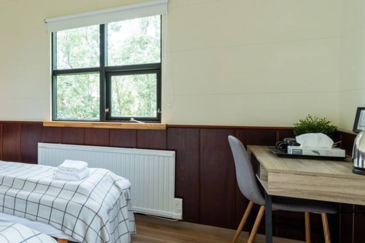 Una habitación con dos camas, una ventana, una mesa y una silla.