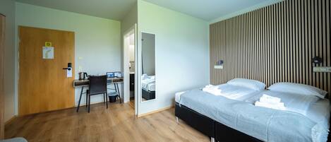 A bedroom with a bed, a desk, and a chair.